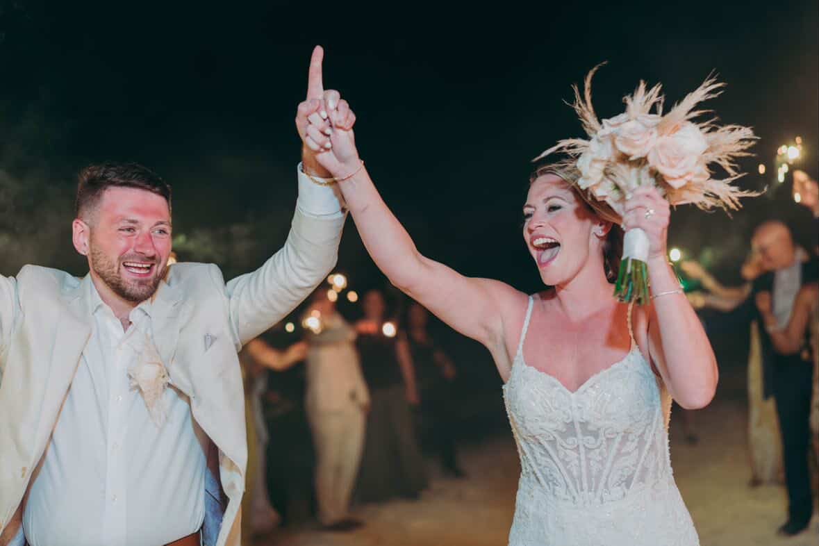 A newlywed couple celebrating together with hands raised